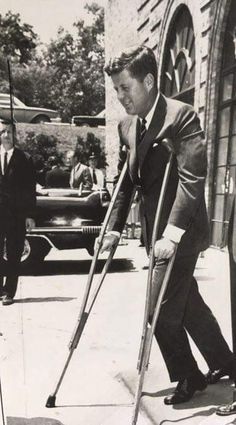 a black and white photo of a man with crutches