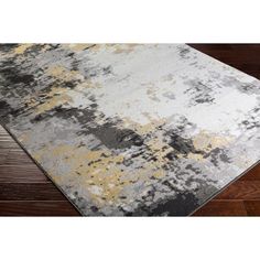 a gray and yellow rug on top of a wooden floor