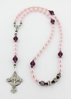 a pink rosary with a cross and beads on the end is laying on a white surface