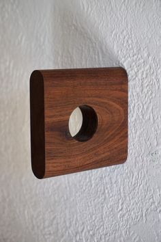 a wooden light switch mounted to the side of a wall with a white painted wall behind it