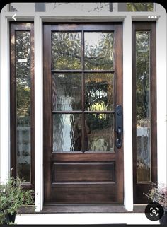 a wooden door with glass panes and sidelights on the front of a house