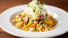 a white plate topped with pasta and veggies covered in parmesan cheese