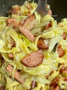 a close up of a plate of food with cabbage and sausage on it's fork