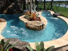 an outdoor swimming pool surrounded by rocks and plants