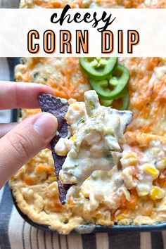 a cheesy corn dip is being held up with a tortilla chip