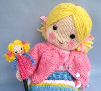 a knitted doll sitting on top of a blue basket with a small doll in it