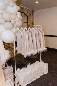 several white dresses and balloons on display in a room