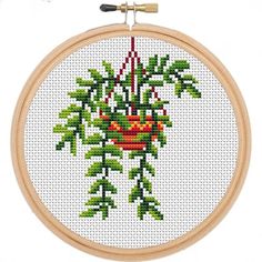 a cross stitch pattern with a potted plant on it's side, hanging from a wooden hoop