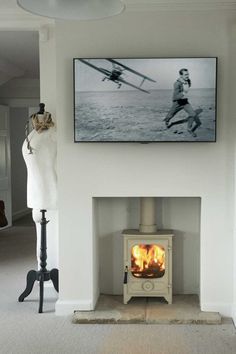 a living room with a fire place next to a painting on the wall and a mannequin standing in front of it