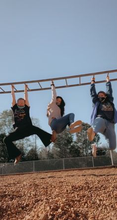 three people are hanging upside down on a rope