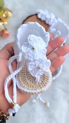 a hand holding a small white crochet purse with flowers on the front and side