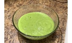 a glass bowl filled with green liquid on top of a counter