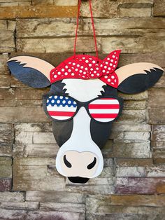 a cow head with sunglasses and an american flag bandana hanging on a brick wall