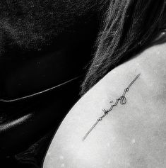 a woman with a tattoo on her upper arm and behind her back is a black - and - white photo