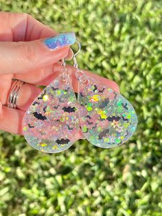 a pair of earrings that have been made out of holographics and are being held in someone's hand