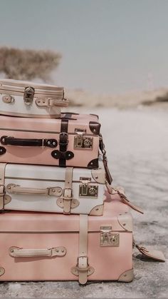 four suitcases stacked on top of each other in front of some sand and trees