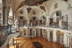 an old library with many bookshelves and sculptures on the walls, along with marble flooring