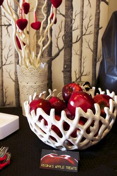 a white bowl filled with red apples on top of a table