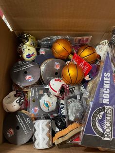 a cardboard box filled with assorted sports memorabilia and basketballs on top of each other