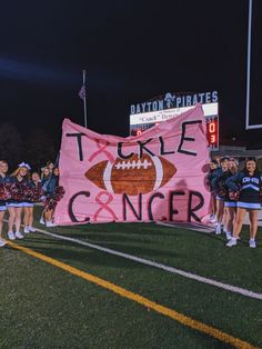 some cheerleaders are holding up a pink banner