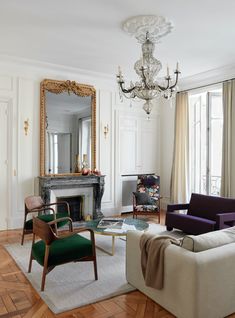 a living room filled with furniture and a chandelier hanging from the ceiling over a fire place