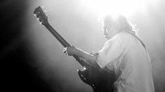 a man with long hair playing an electric guitar in front of spotlights on a stage