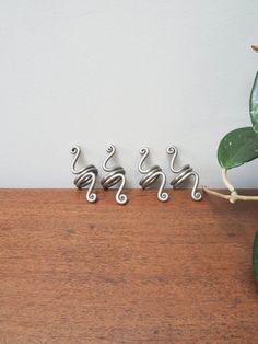 three metal spirals sitting on top of a wooden table next to a potted plant