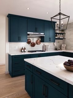 a large kitchen with blue cabinets and white counter tops, an island in the middle