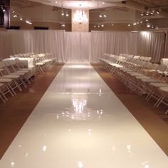 rows of white folding chairs lined up on the floor in front of a curtained wall