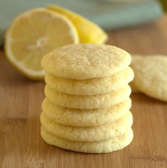 a stack of lemon shortbread cookies sitting on top of a wooden table next to sliced lemons