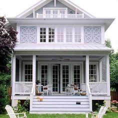 two lawn chairs sitting in front of a white house with porches and balconies