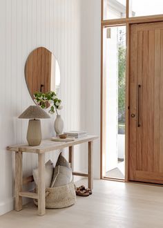 a wooden table sitting in front of a mirror on top of a wall next to a door