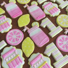 decorated cookies with pink and yellow icing on a wooden table next to lemon slices