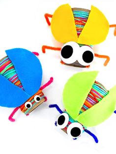 three colorfully decorated bugs sitting next to each other on a white surface with black eyes