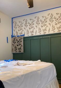 a bed with white sheets and blue tape on the headboard is in front of a green paneled wall