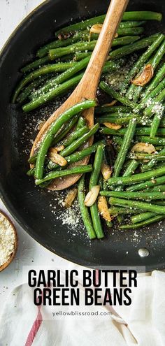 garlic butter green beans in a skillet with wooden spoon and salt on the side