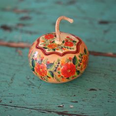 a small painted pumpkin sitting on top of a wooden table next to a green wall