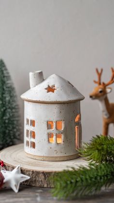 a small white house sitting on top of a tree stump next to a christmas ornament