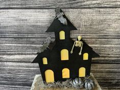 a halloween decoration with a skeleton on top of a black house and two pumpkins