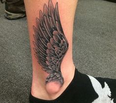 a black and white photo of a person's foot with a bird tattoo on it