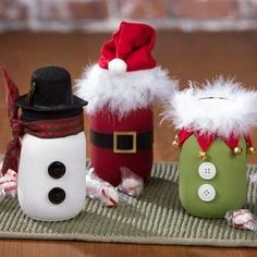 three christmas decorations sitting on top of a green mat next to a snowman and santa hat