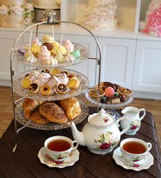 a table topped with three tiered trays filled with pastries and tea cups