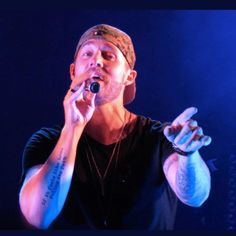 a man holding a microphone up to his mouth while standing in front of a blue light