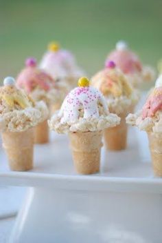 small ice cream cones with sprinkles and candies in them on a white tray