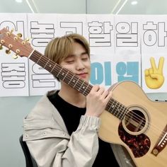 a young man holding an acoustic guitar in front of his face