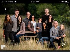 a large group of people are posing for a photo in the grass with trees behind them