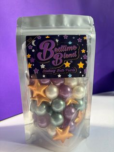 a bag filled with lots of different colored balls and stars on top of a white table