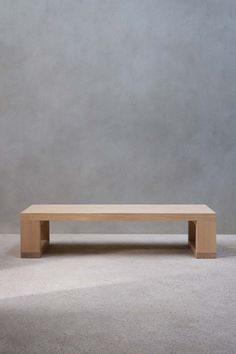 a wooden bench sitting on top of a white floor next to a gray wall in an empty room