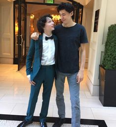 two young men standing next to each other in front of a hotel room door way