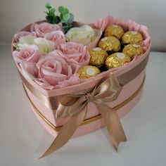 a heart shaped box filled with pink roses and chocolates on a white table top